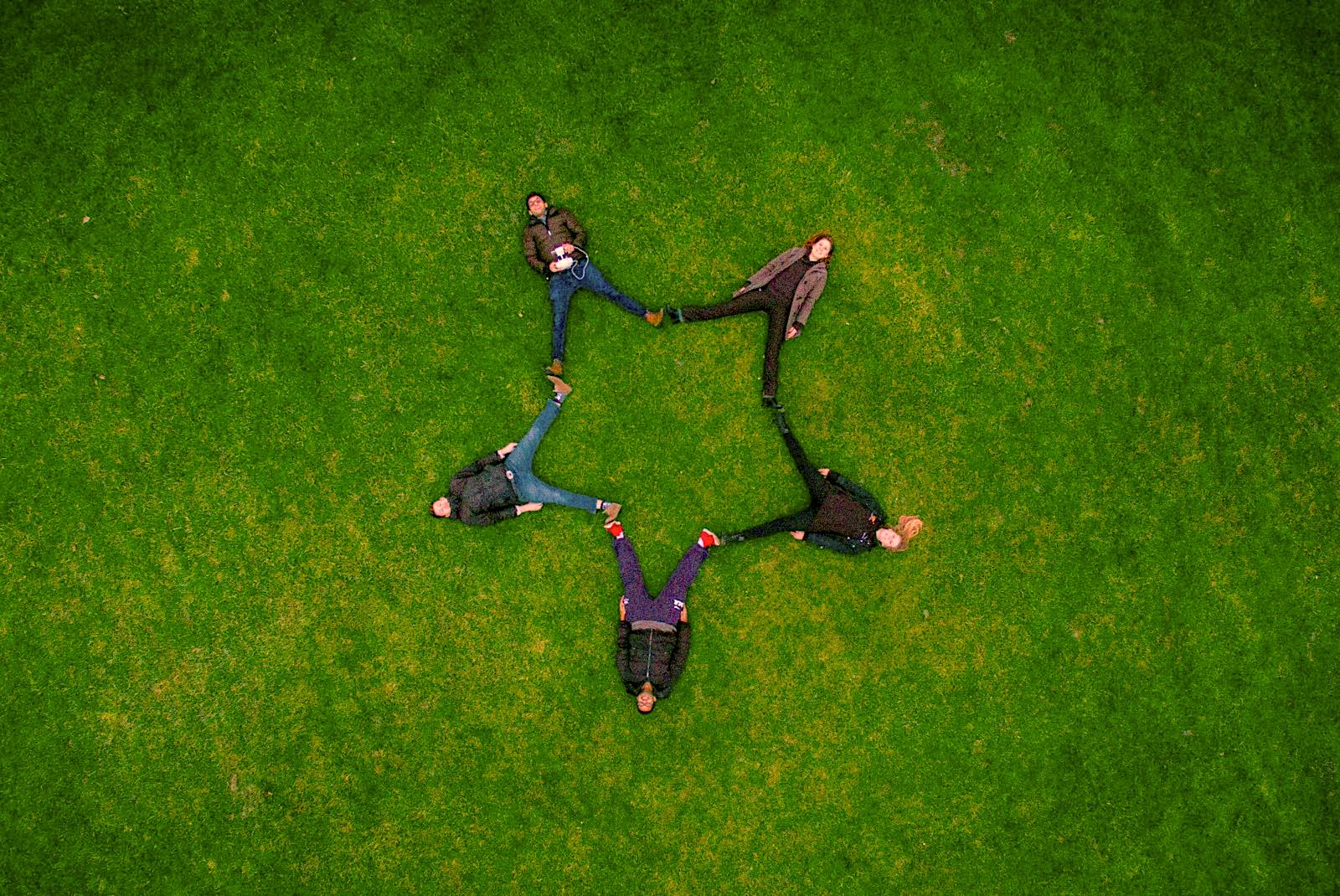 5 people laying on the ground in a star shape